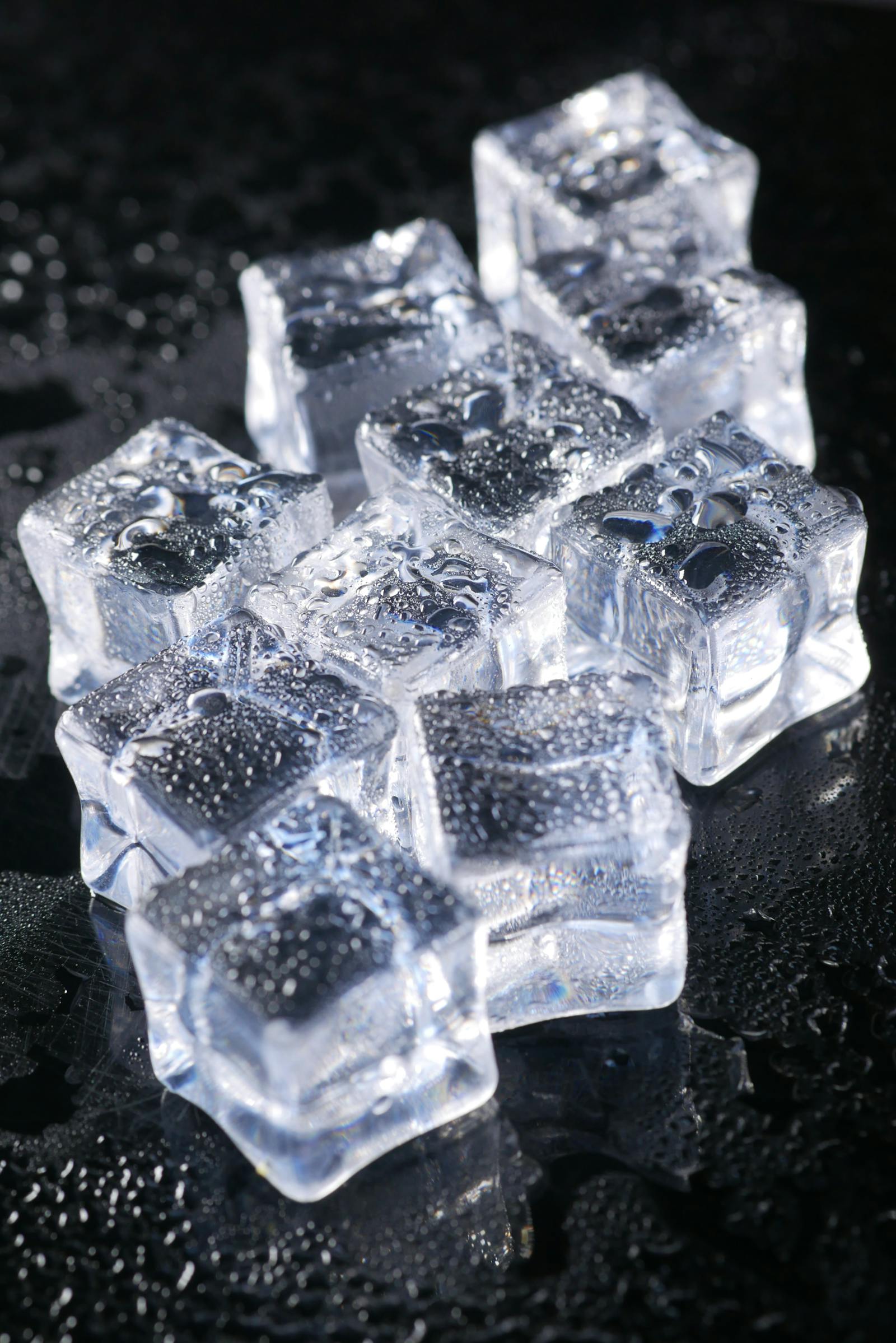 Cubos de hielo translúcidos apilados sobre superficie oscura húmeda — referencia visual a la variante "Nice Ice Baby" del NeeDoh Nice Cube.