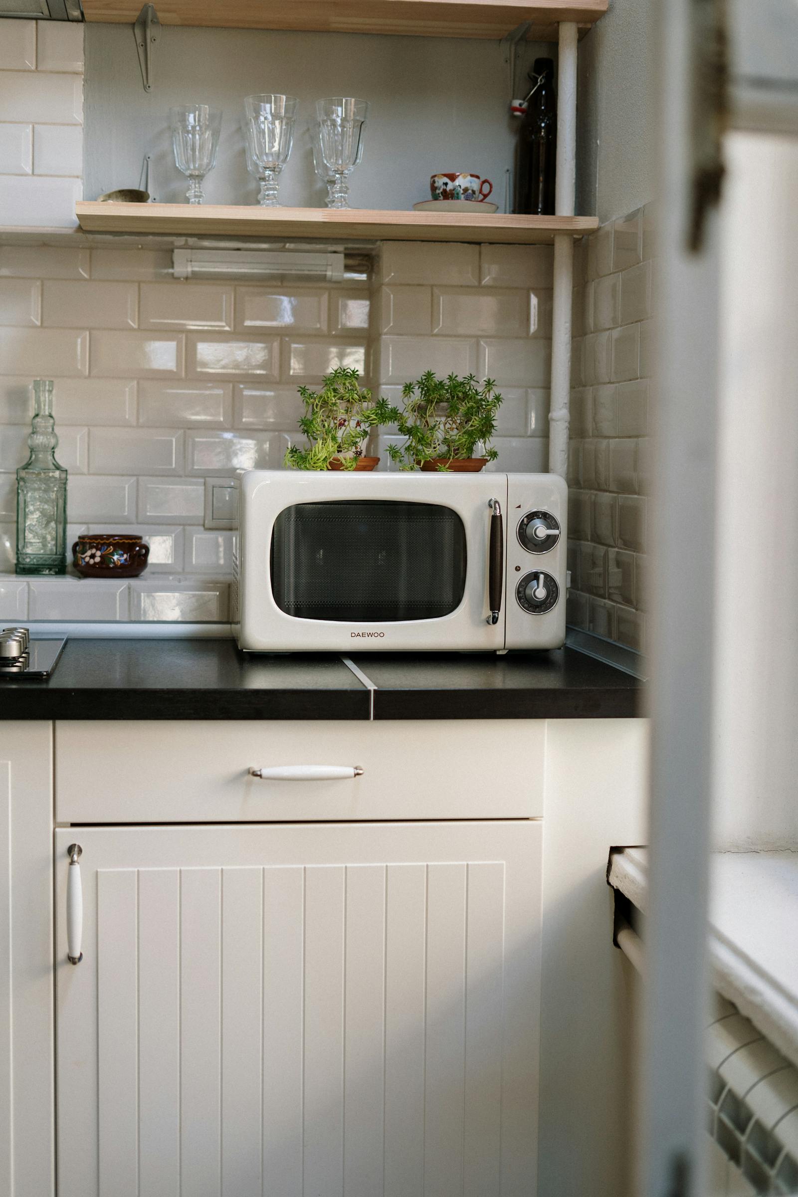 Microondas blanco vintage sobre mueble de cocina rústico con plantas — el electrodoméstico al que no debes meter un squishy de gel.